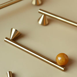 Poignées et boutons d'armoire Deauville de la marque Renfan, en métal brillant, fixés sur une porte en bois clair.